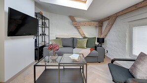 Uma sala de estar moderna com televisão de tela plana, mesa de centro de vidro, sofá e claraboia.
