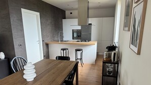 A modern kitchen with a central island, bar stools, and a dining table with chairs. - Accogliente appartamento immerso nel parco del Ticino (Castelnovate)