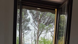 A sliding glass door leading to a balcony with a view of a green lawn and trees. - Accogliente appartamento immerso nel parco del Ticino (Castelnovate)
