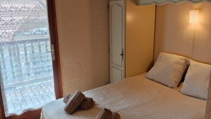 A bedroom with a bed, two rolled towels, a wardrobe, and a window with a view. - L'ANCRE BLEU ENTRE FILET ET MAREE; HOUSE IN THE HEART OF CAPBRETON HARBOR (Capbreton)