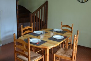 Ein Esstisch mit sechs Stühlen, eine Uhr an der Wand und eine Treppe im Hintergrund.