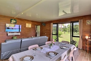 Un coin repas avec une table dressée pour quatre personnes, un canapé et un téléviseur fixé au mur.