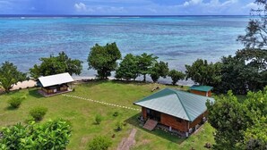 Una proprietà costiera con un'area verde, due edifici con tetti verdi e vista sull'oceano.