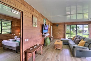 Une pièce avec un plancher en bois, comprenant un lit, un canapé, une télévision et une petite table.