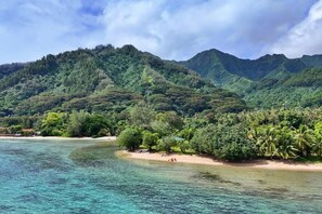A tropical beach with clear turquoise water, lush green hills, and a sandy shore. - Fare Heimery - Plage Lagon Privée (Moorea-Maiao)