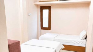 A small, single-room accommodation with two beds, a window, and a ceiling fan. - Kanha Homestay Near Mahakal Mandir (Ujjain)