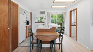 Eine moderne Küche mit Essbereich, Holzschränken und Blick auf Grünflächen.