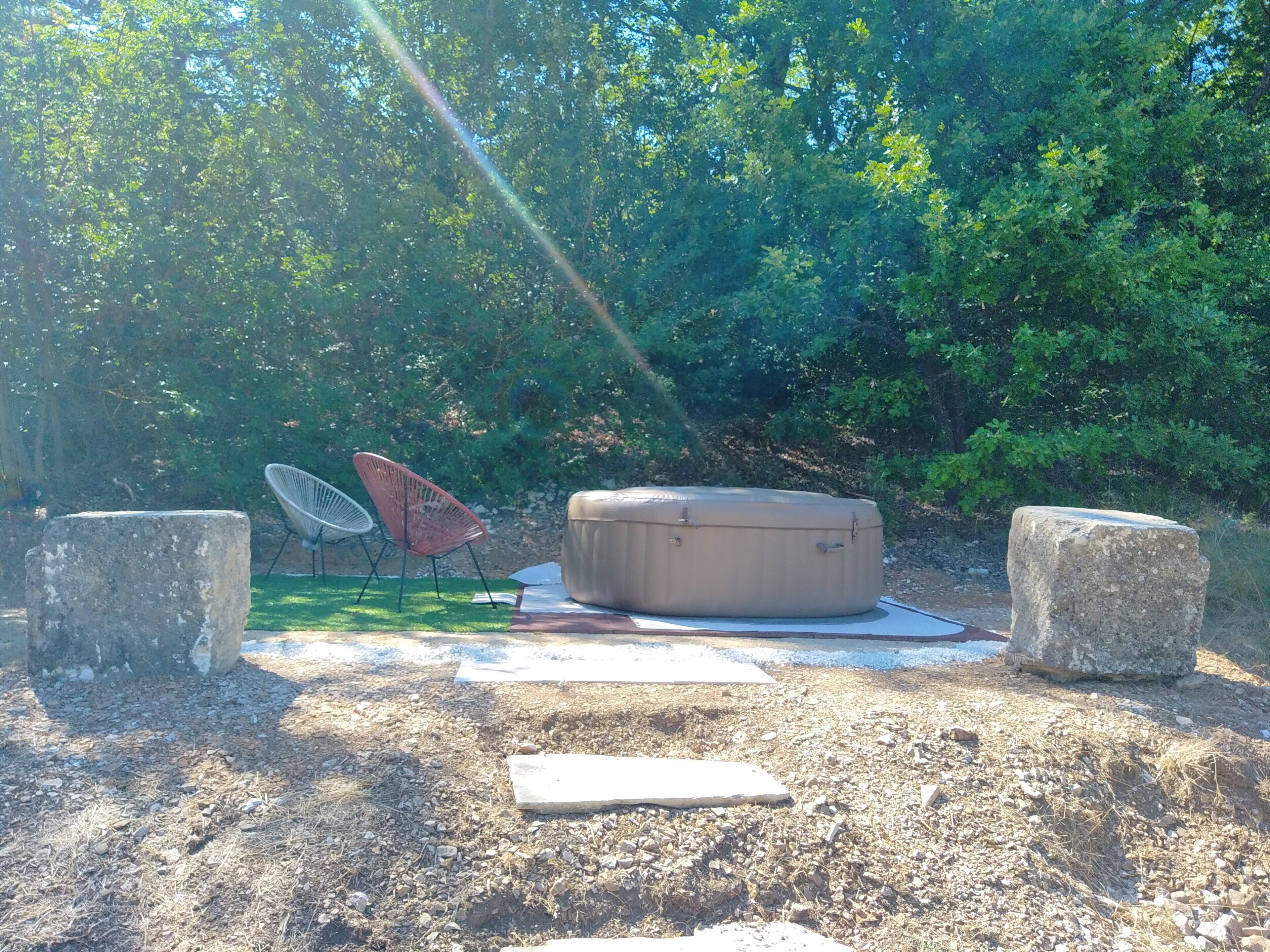 An outdoor seating area with a stone bench, two chairs, and a large round table.