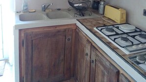 Una cucina con pensili in legno, un fornello a gas, un lavello e un tostapane giallo.