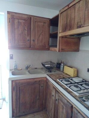 Eine Küche mit Holzschränken, einem Gasherd, einer Spüle und einem gelben Toaster.