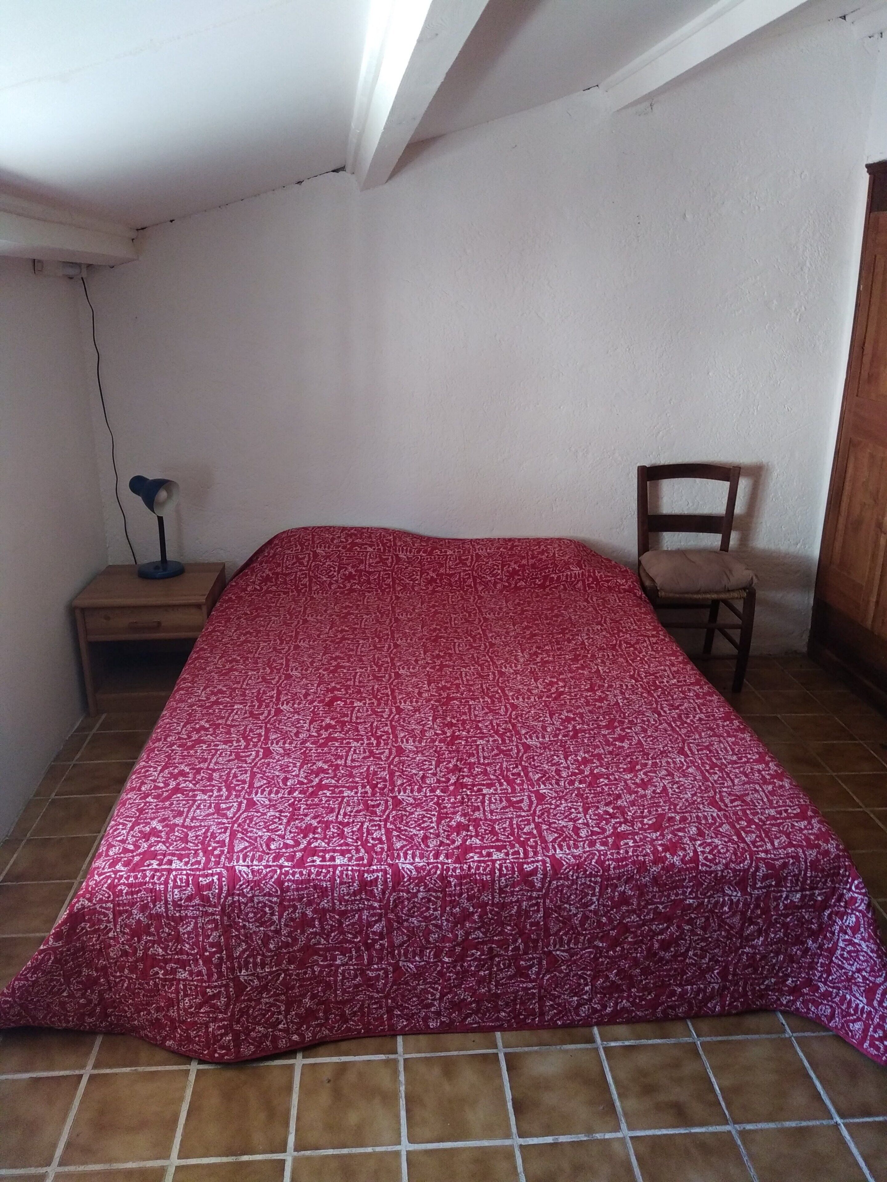 Ein Zimmer mit einem Bett, einem Sessel, einem Nachttisch und einem Schreibtisch.