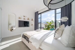 Un dormitorio moderno con una cama grande, un televisor, un espejo y vistas al exterior.
