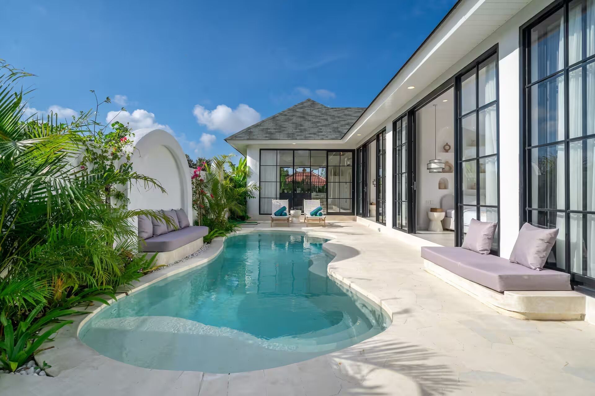 A modern house with a swimming pool, outdoor seating, and large windows.