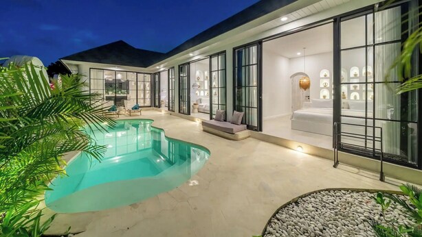 A modern house with a swimming pool, large glass doors, and a well-lit interior. - White Shell Villa 1 (badung)