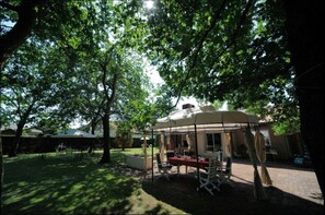 A covered outdoor seating area with tables and chairs, surrounded by trees. - Guest Room “Les Genêts” with Shared Terrace, Wi-Fi, and Air Conditioning (Gujan-Mestras)