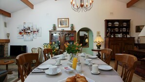 Uma área de refeições com uma mesa posta para o café da manhã, incluindo croissants, um vaso com flores e diversos itens para o café.