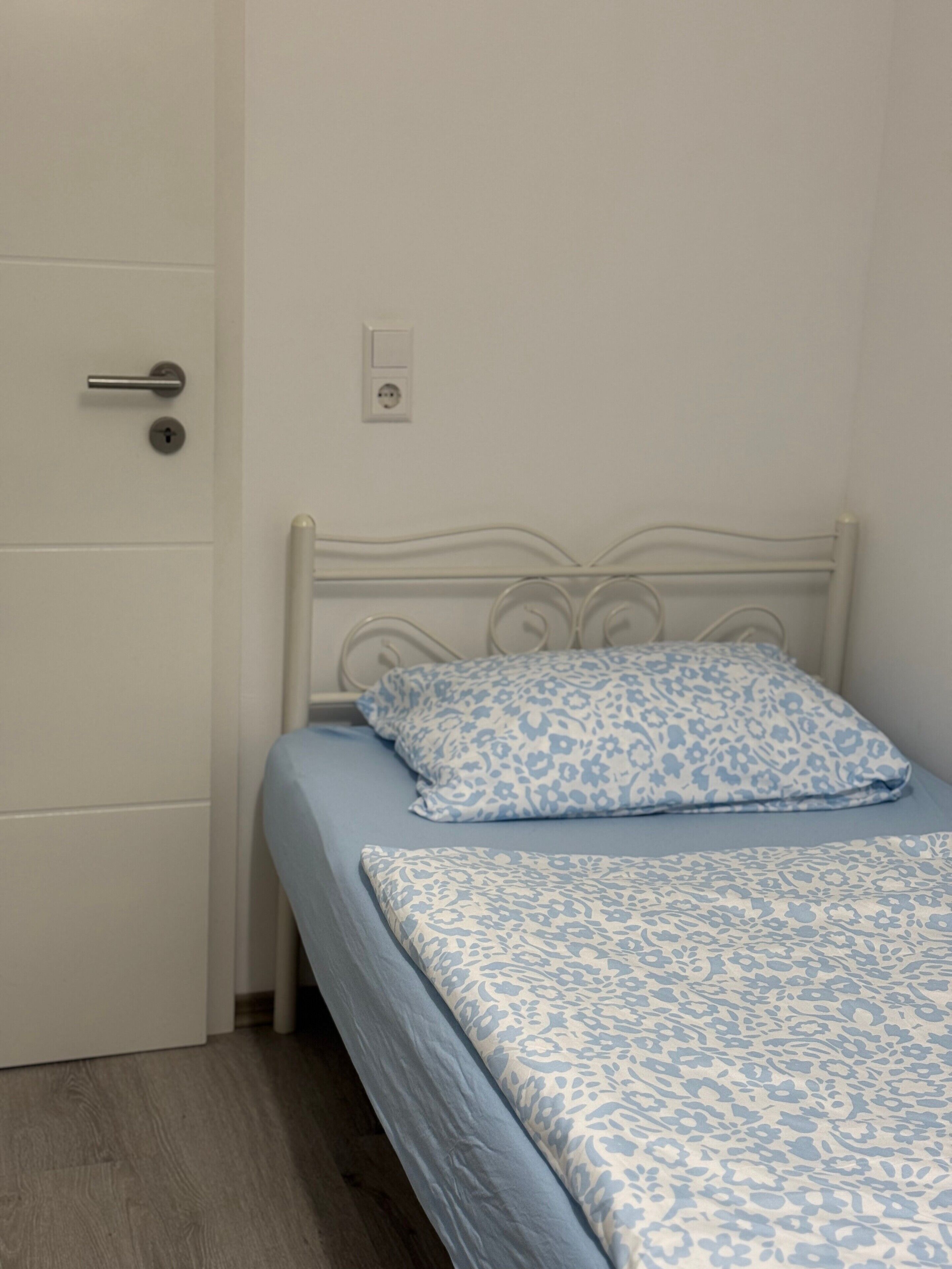 Een slaapkamer met een bed, een deur en een stopcontact.