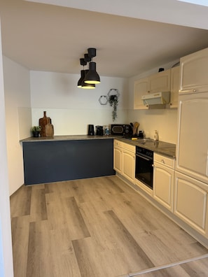Eine moderne Küche mit einer zentralen Kochinsel, weißen Schränken, einer schwarzen Arbeitsplatte und Holzboden.