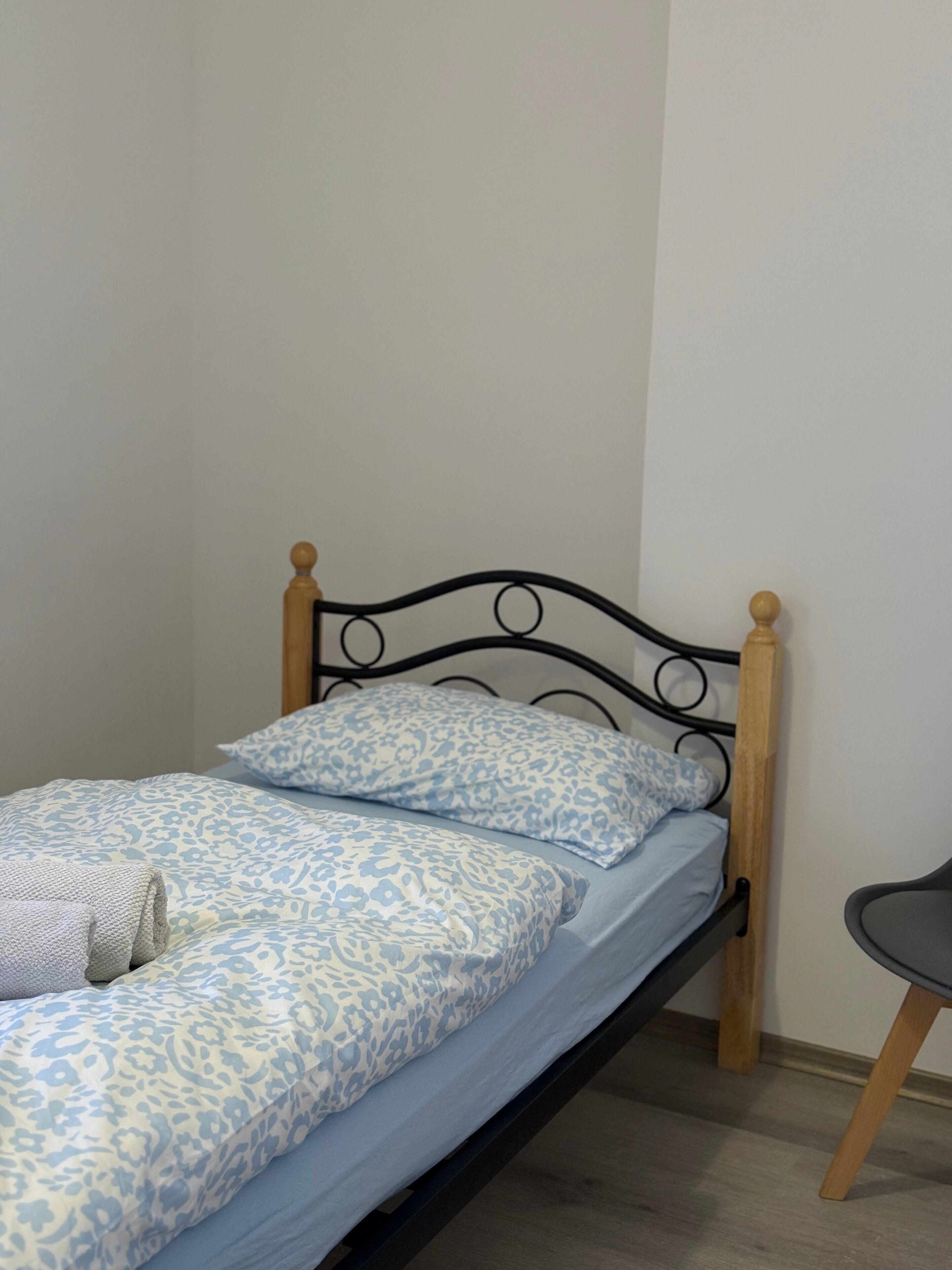 Una cama individual con cabecera de madera, colcha estampada azul y almohadas a juego.