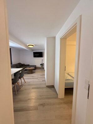 Ein stilvoller Wohnbereich mit Essplatz, einer Couch, einem Fernseher und einem Bett.