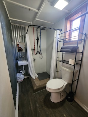 Ein kleines Badezimmer mit Dusche, Toilette und Waschbecken.