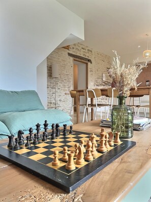 A chessboard set up on a wooden table in a room with a stone wall and a lofted ceiling. - "Le clos du bon temps" (Lugny)