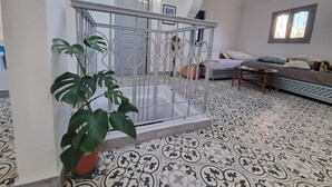 A room with a patterned floor, a bed with pillows, a sofa, a hanging chair, and a potted plant. - Tangier medina Riad Sea view and Spain (Tanger)