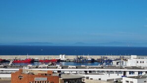 A coastal port with industrial buildings and ships, including a prominent red vessel. - Tangier medina Riad Sea view and Spain (Tanger)