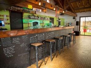 A bar area with stools, a chalkboard menu, and a bar counter with bottles. - Cozy mobile home - 6 guests (Saint-Hilaire-de-Riez)