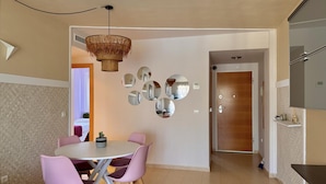 A modern dining area with a round table, pink chairs, a woven ceiling light, and a wall with circular mirrors. - Apartment with terrace - 4 guests (Vergel)