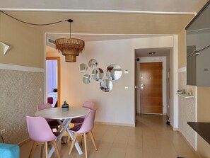 A modern dining area with a round table, pink chairs, a woven ceiling light, and a wall with circular mirrors. - Apartment with terrace - 4 guests (Vergel)