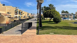 A residential area with yellow buildings, a paved walkway, and a gazebo. - Apartment with terrace - 4 guests (Vergel)