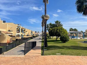 A residential area with yellow buildings, a paved walkway, and a gazebo. - Apartment with terrace - 4 guests (Vergel)