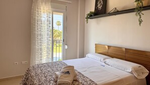 A hotel room with a bed, a balcony with a view, a plant on the wall, and a painting. - Apartment with terrace - 4 guests (Vergel)