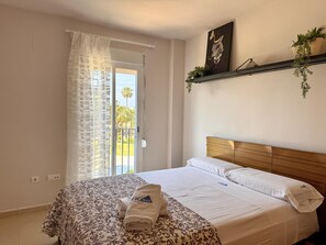 A hotel room with a bed, a balcony with a view, a plant on the wall, and a painting. - Apartment with terrace - 4 guests (Vergel)