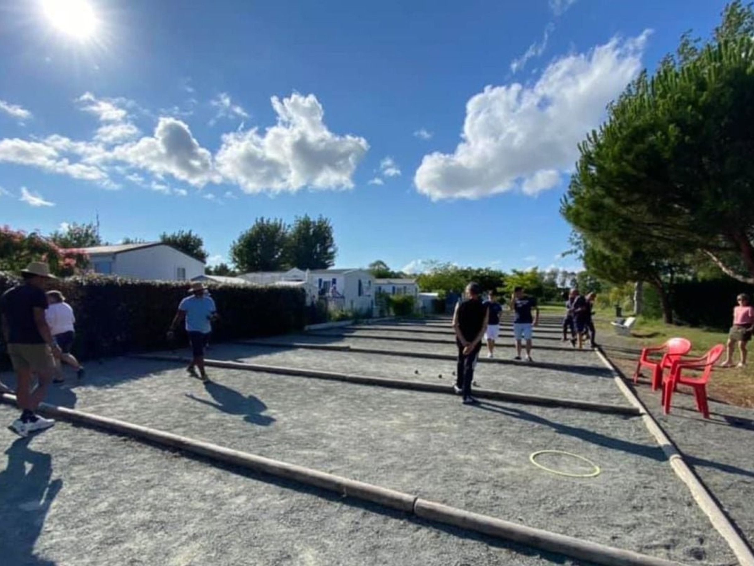 Un espacio al aire libre con suelo pavimentado, algunas personas y una hilera de sillas rojas.