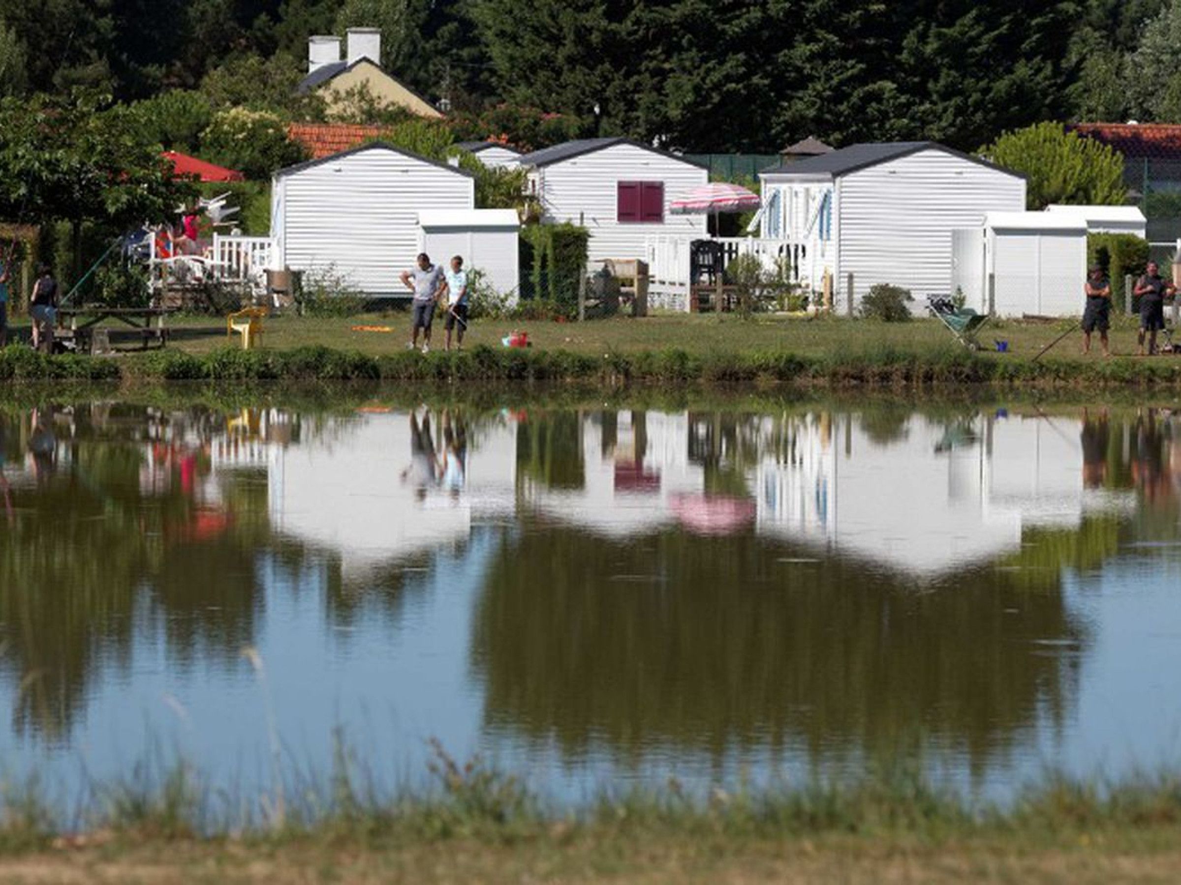 Un lac paisible où se reflètent les bâtiments et les personnes situés à proximité.