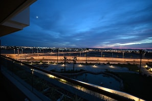 Nachtsicht auf eine Skyline mit beleuchteten Straßen, einem Kreisverkehr und fernen Stadtlichtern.