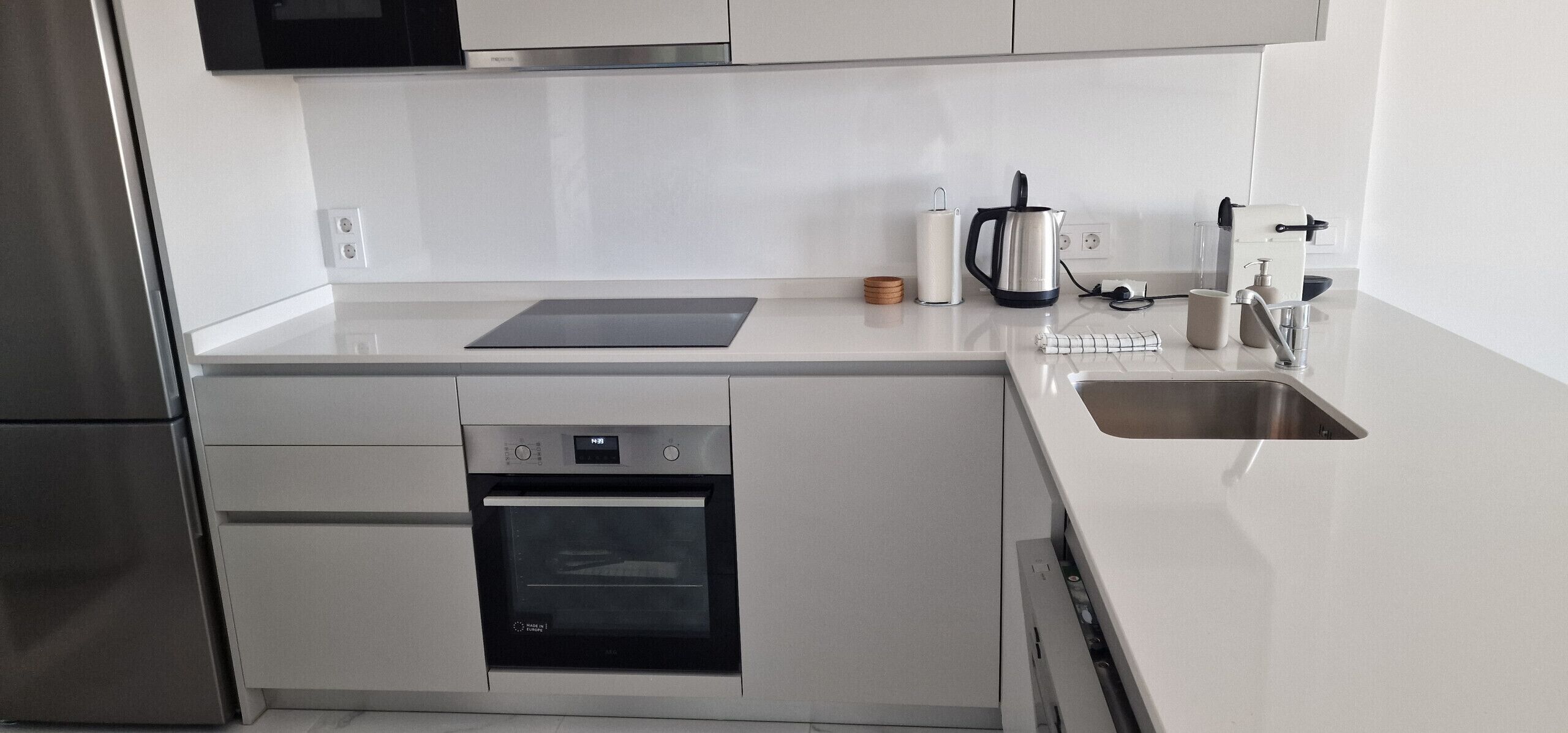 A modern kitchen with stainless steel appliances, a built-in oven, a microwave, and a coffee maker.