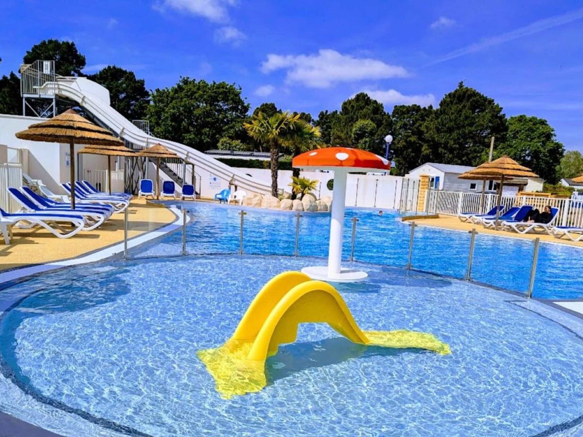A swimming pool with slides, lounge chairs, and umbrellas.