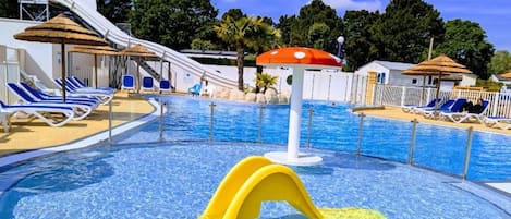 Ein Schwimmbecken mit Rutschen, Liegestühlen und Sonnenschirmen.