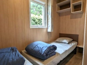 A small, single-bed room with wooden walls, a window, and built-in shelves. - Chalet, pets welcome - 4 guests (Saint-Hilaire-de-Riez)