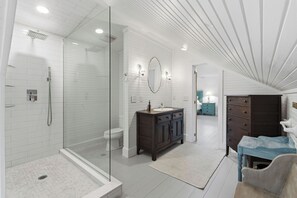 Une salle de bain moderne avec une douche à parois de verre, un meuble-lavabo en bois foncé et un sol carrelé de couleur blanche.
