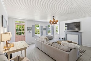Una sala de estar con sofá, televisor, chimenea y una puerta con contraventanas.