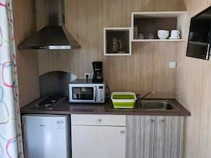 A compact kitchenette with a microwave, coffee maker, and a small sink. - Charming chalet, pets welcome - 2 guests (Saint-Hilaire-de-Riez)