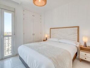 Ein Schlafzimmer mit Bett, Kleiderschrank, Nachttisch und einer Hängeleuchte.