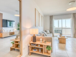 Ein modernes Wohnzimmer mit einer Couch, einem Couchtisch, einem Fernseher und Blick auf einen Balkon.