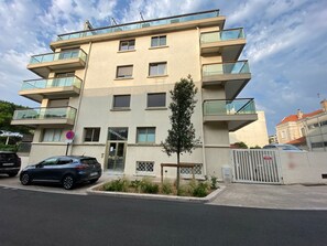 A multi-story building with balconies, a gated entrance, and a sign indicating a no-parking zone. - Studio sea view - 2 guests (Arcachon)