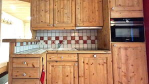Eine Küche mit Holzausstattung, gefliestem Rücksprung und einem eingebauten Backofen.
