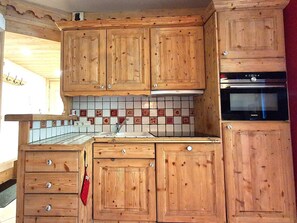 Eine Küche mit Holzausstattung, gefliestem Rücksprung und einem eingebauten Backofen.